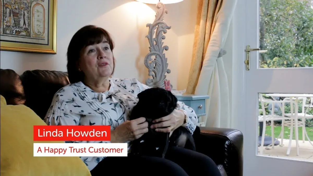 Linda Howden at home on her sofa with her dog, telling her Trust story