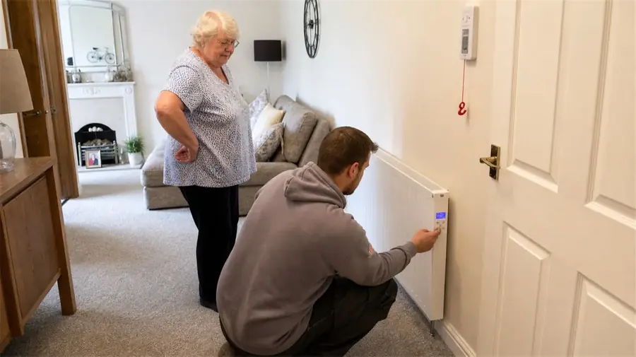A Trust engineer showing a customer the controls on her new radiator at home